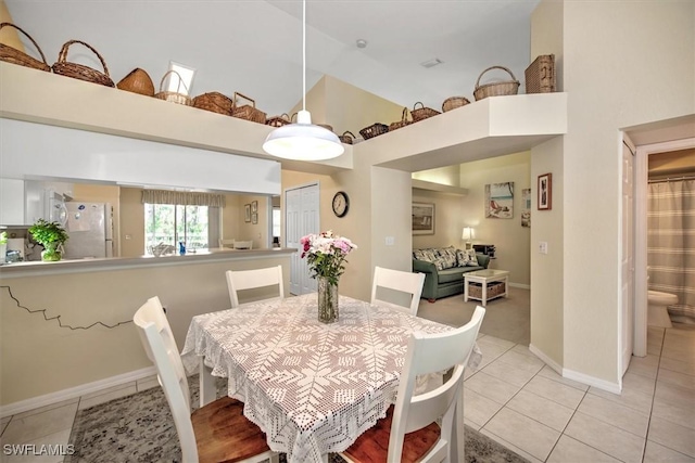 dining space with baseboards, light tile patterned flooring, and a high ceiling