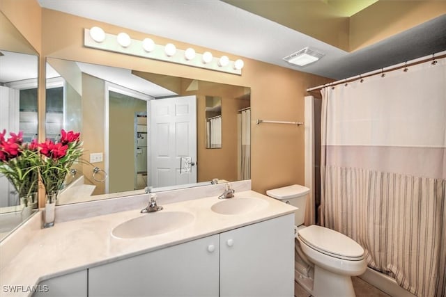 bathroom with visible vents, a sink, toilet, and double vanity