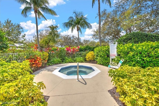 view of swimming pool with fence and a community hot tub