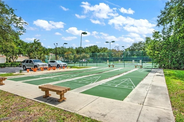 view of community with a tennis court, fence, and shuffleboard