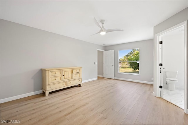 unfurnished bedroom featuring connected bathroom, light wood-style flooring, baseboards, and ceiling fan