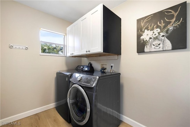 laundry area featuring cabinet space, washer and clothes dryer, baseboards, and light wood finished floors