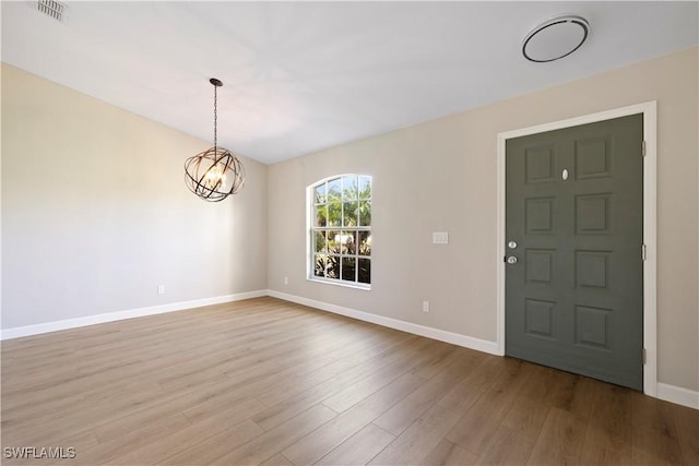 foyer entrance featuring a chandelier, visible vents, baseboards, and wood finished floors