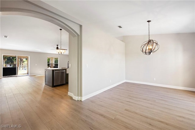 empty room with a chandelier, light wood-style flooring, and baseboards