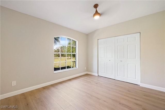 unfurnished bedroom featuring a closet, light wood-style flooring, and baseboards