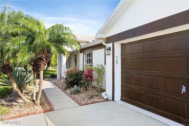 entrance to property with an attached garage and stucco siding