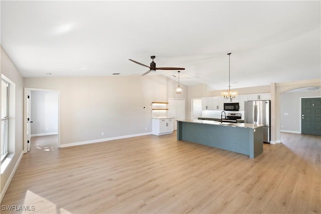 kitchen with lofted ceiling, a kitchen island with sink, ceiling fan with notable chandelier, white cabinets, and appliances with stainless steel finishes