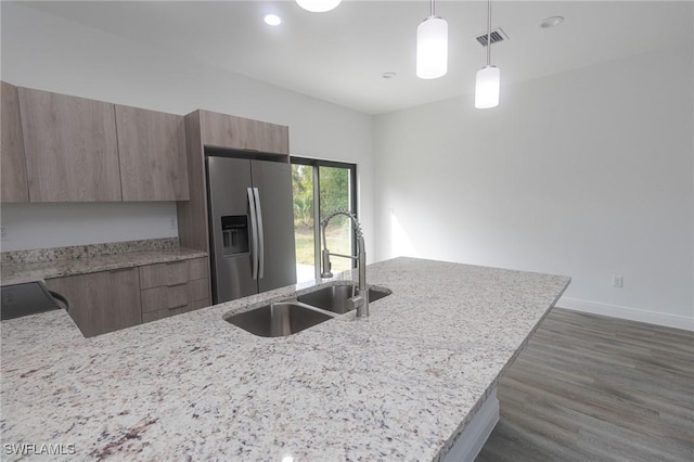 kitchen with dark wood-type flooring, modern cabinets, a sink, stainless steel fridge with ice dispenser, and light stone countertops