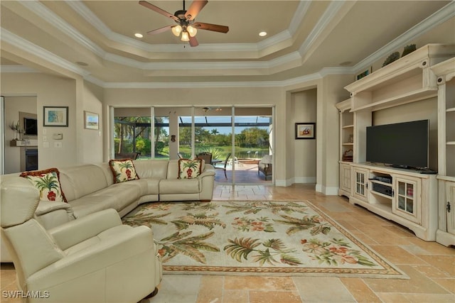 living room featuring ceiling fan, stone tile floors, a raised ceiling, and crown molding