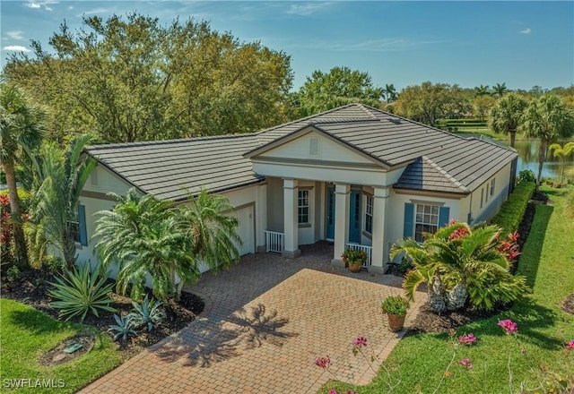 view of front facade with an attached garage, a tile roof, decorative driveway, and stucco siding