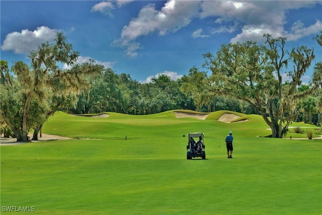 surrounding community featuring view of golf course and a lawn