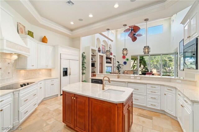 kitchen featuring visible vents, custom range hood, decorative backsplash, black appliances, and a sink