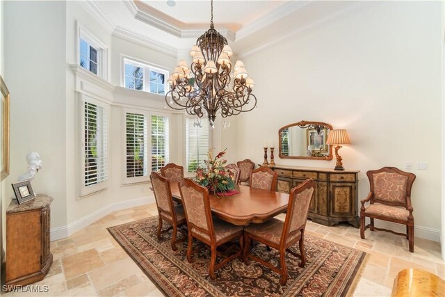 dining space featuring a raised ceiling, ornamental molding, a chandelier, and stone tile flooring