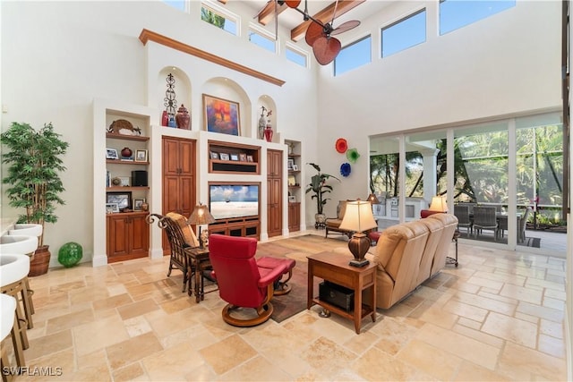 living room with ceiling fan, baseboards, and stone tile flooring