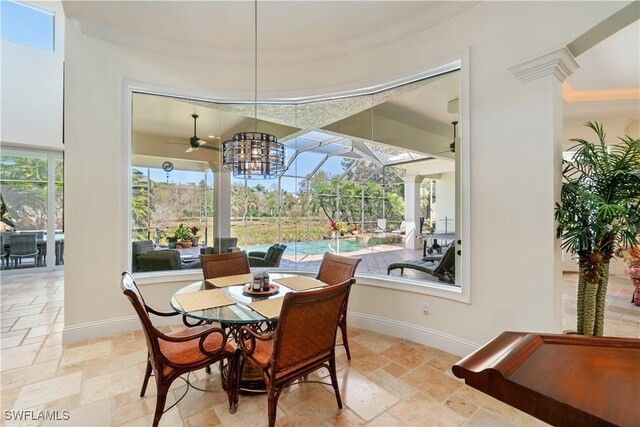 dining space featuring baseboards, stone tile floors, a ceiling fan, and a sunroom