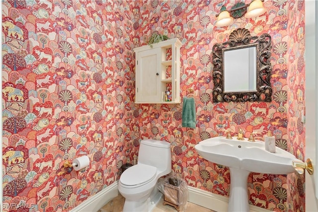 bathroom featuring baseboards, toilet, and wallpapered walls