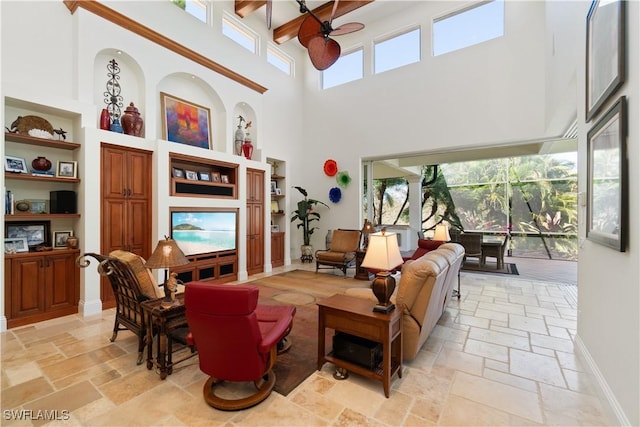 living room featuring ceiling fan, baseboards, and stone tile flooring