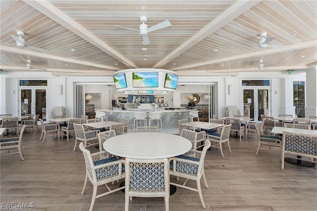 dining space featuring french doors, beam ceiling, light wood-style flooring, and a ceiling fan