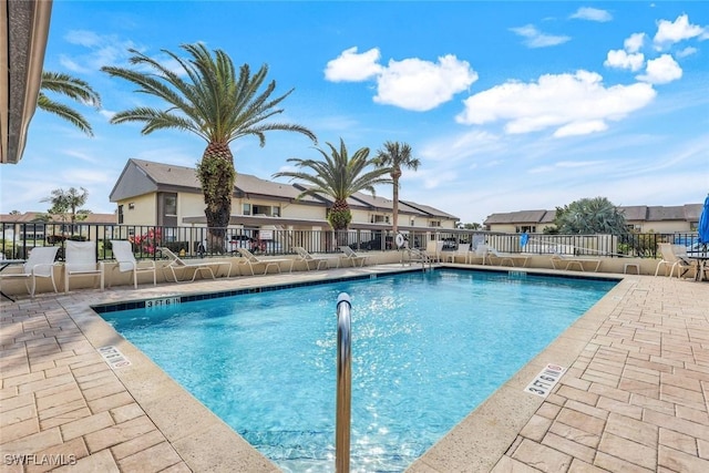 pool with a patio, fence, and a residential view