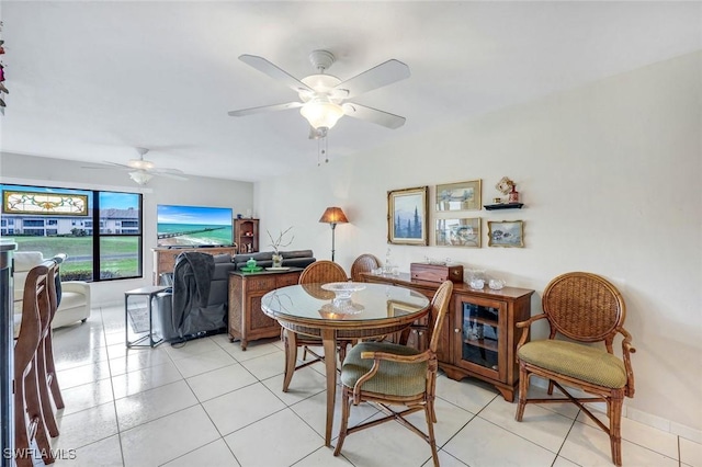 dining space with a ceiling fan, baseboards, and light tile patterned floors