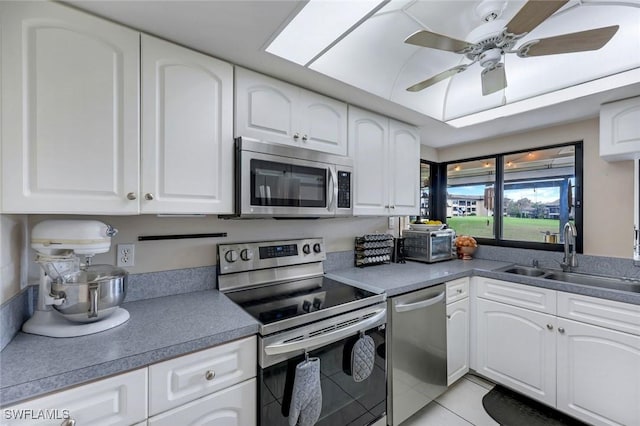 kitchen featuring light tile patterned floors, white cabinetry, stainless steel appliances, and a sink