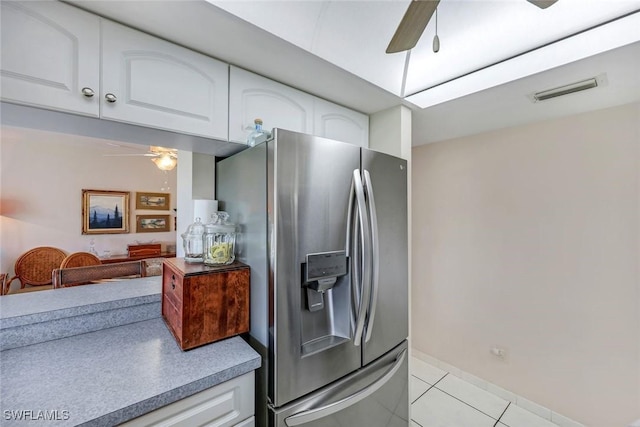 kitchen featuring light tile patterned floors, visible vents, white cabinets, a ceiling fan, and stainless steel fridge with ice dispenser