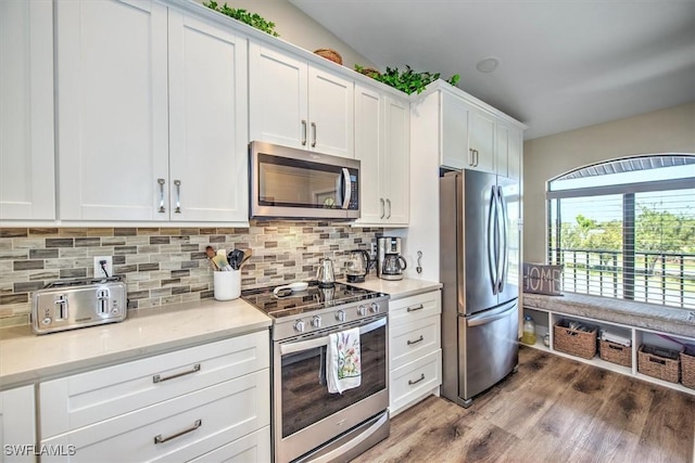 kitchen with tasteful backsplash, white cabinetry, stainless steel appliances, and wood finished floors