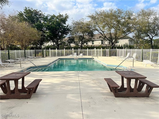 community pool with a patio area and fence