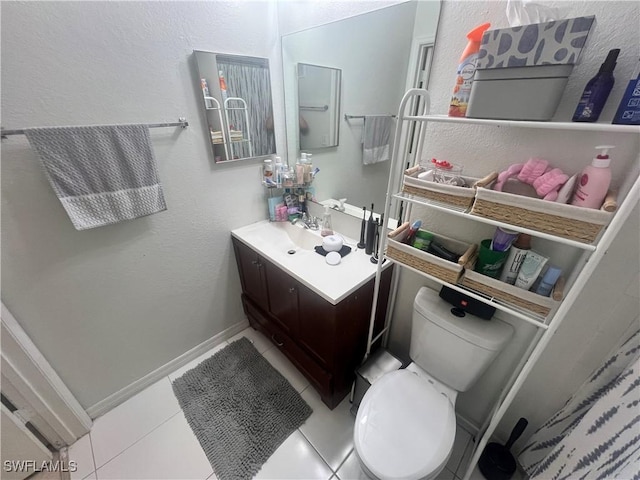 bathroom with tile patterned flooring, toilet, vanity, and baseboards