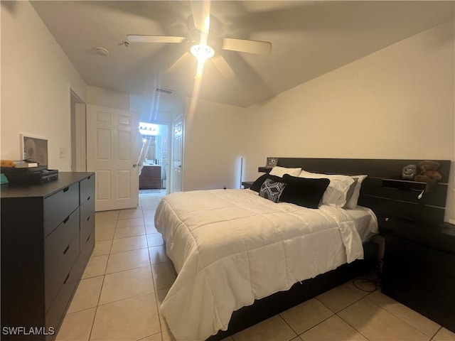 bedroom with ensuite bath, light tile patterned flooring, visible vents, and ceiling fan