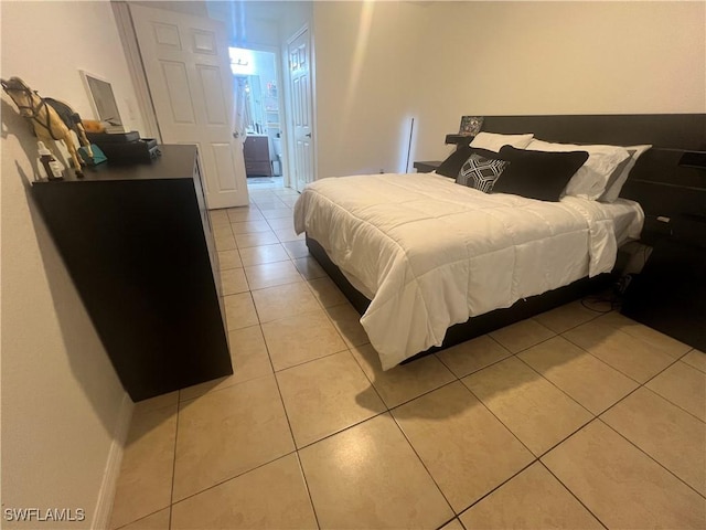 bedroom with connected bathroom, baseboards, and light tile patterned flooring