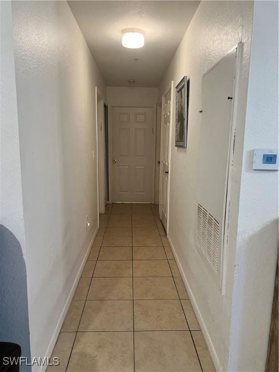 hall with light tile patterned floors and baseboards