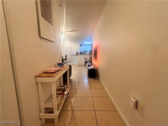 hall featuring light tile patterned flooring and baseboards