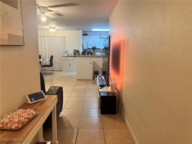 corridor featuring visible vents, baseboards, and light tile patterned flooring