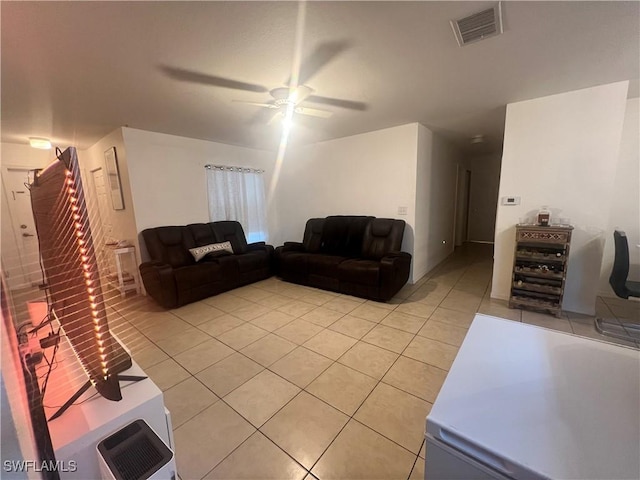 living area featuring light tile patterned floors, visible vents, a ceiling fan, and stairway