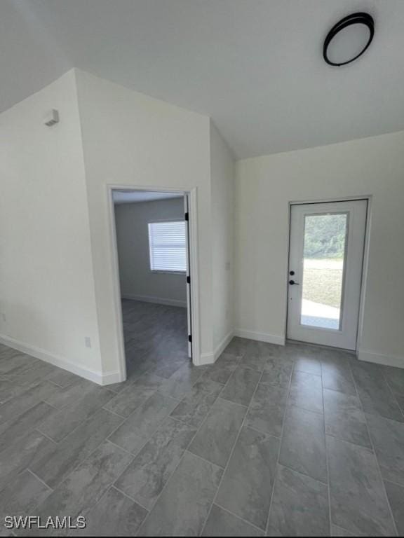 interior space featuring lofted ceiling, baseboards, and a healthy amount of sunlight