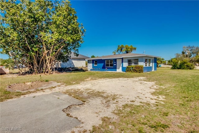 view of front of home with dirt driveway and a front yard