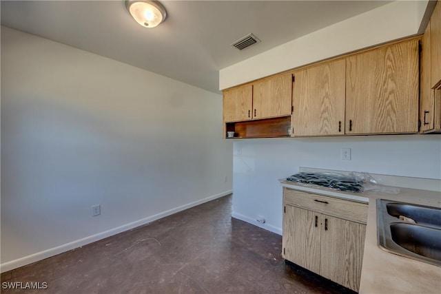 kitchen with light countertops, visible vents, light brown cabinets, a sink, and baseboards