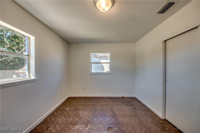 spare room featuring baseboards, visible vents, and tile patterned floors