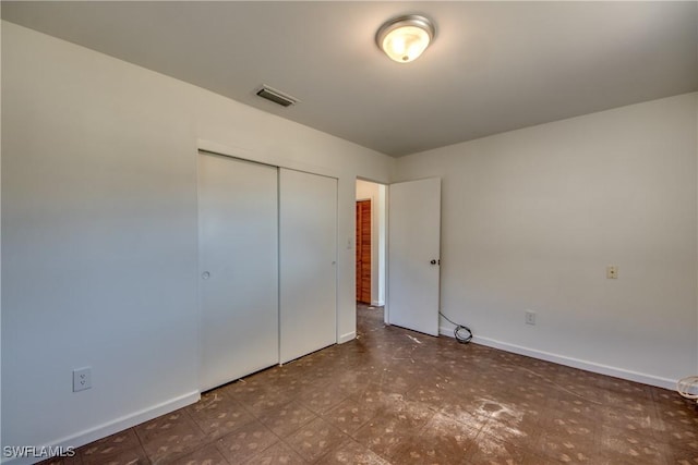 unfurnished bedroom with a closet, visible vents, baseboards, and tile patterned floors