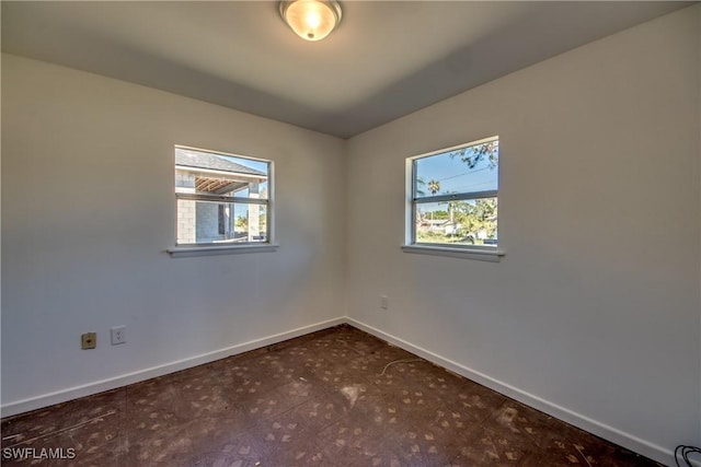 spare room featuring a wealth of natural light, baseboards, and tile patterned floors