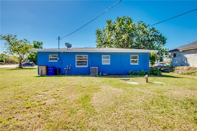 rear view of house with central AC and a yard