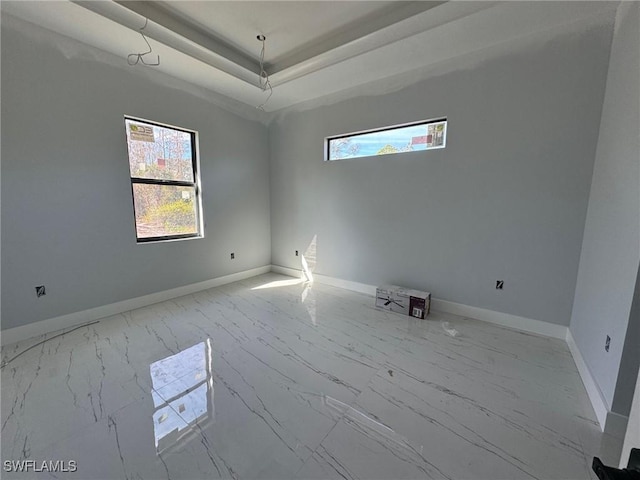 spare room with a tray ceiling and baseboards