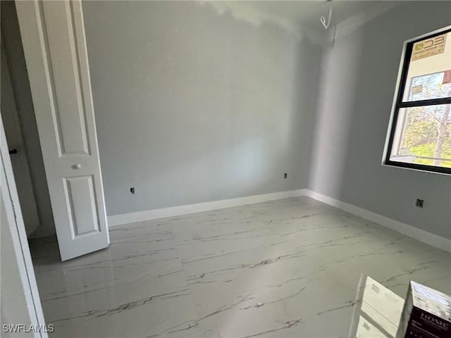 empty room featuring marble finish floor and baseboards