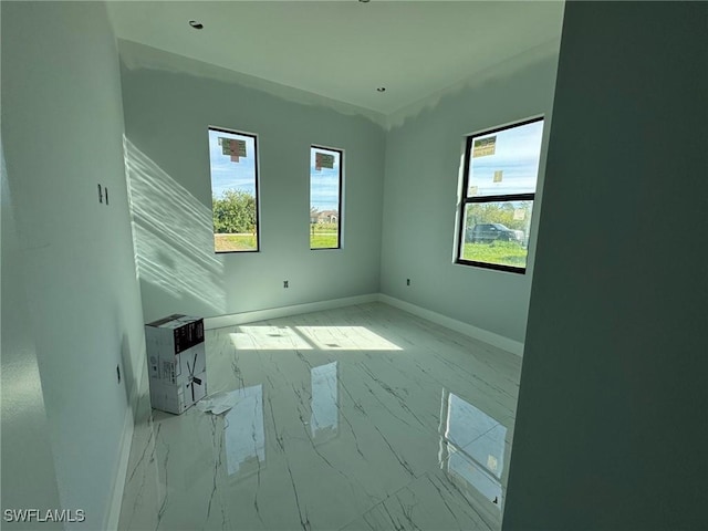 unfurnished room featuring marble finish floor and baseboards