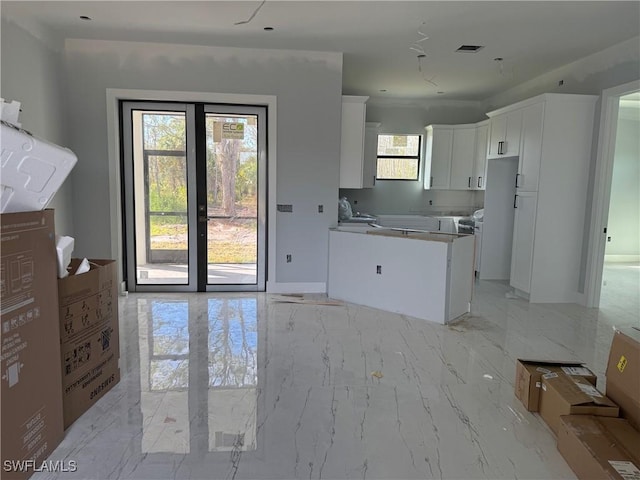 kitchen featuring marble finish floor, white cabinets, visible vents, and a healthy amount of sunlight