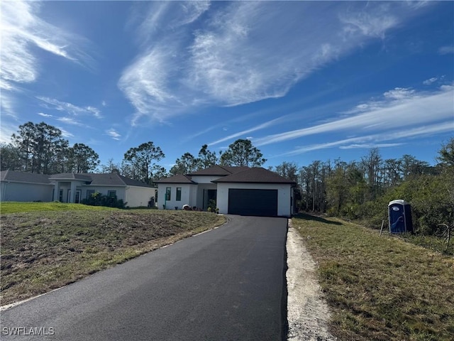 single story home with a garage, aphalt driveway, and a front lawn