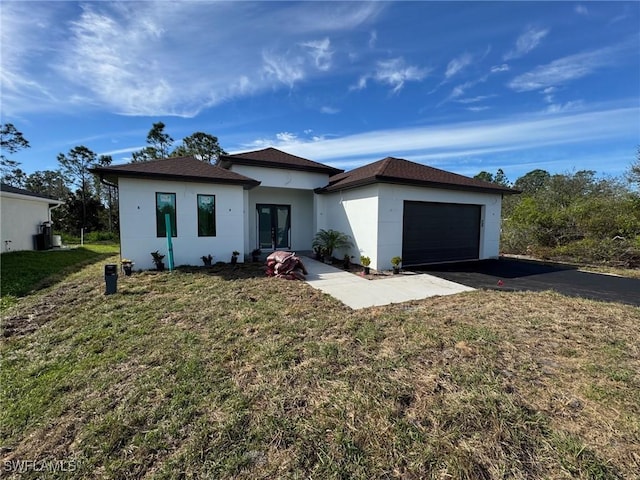 view of front of home featuring aphalt driveway, french doors, stucco siding, a front yard, and a garage