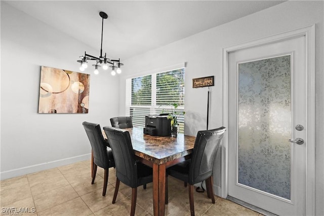 dining room featuring lofted ceiling, light tile patterned flooring, a notable chandelier, and baseboards