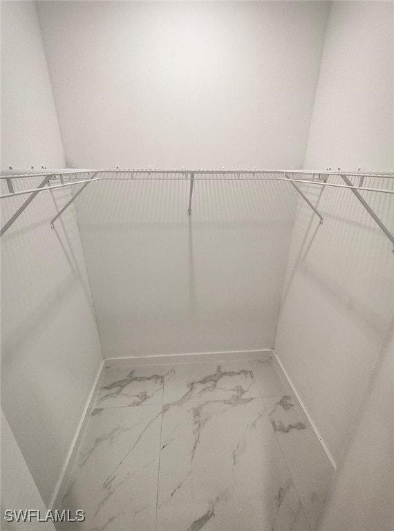 walk in closet with marble finish floor